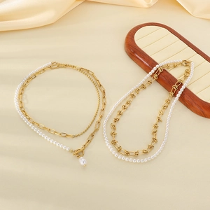Detail of layered Baroque pearl and gold chain necklaces on a silk satin background