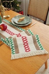 Close-up of cotton linen Christmas table runner with red and green tassels and stripes