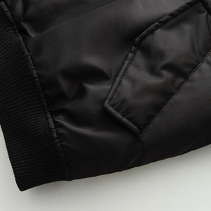 Detailed close-up of shiny black nylon fabric and ribbed knit cuffs on bomber jacket