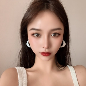 Elegant white acrylic C-shaped hoop earrings worn by a model against a soft background