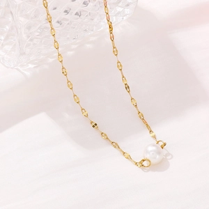 Macro shot of gold flat link chain necklace featuring a single white pearl pendant