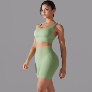 Dettaglio del set pantaloncini yoga a vita alta verde salvia e reggiseno sportivo fitness