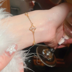 Close-up of elegant gold flower charm bracelet with zircons and pearls on wrist
