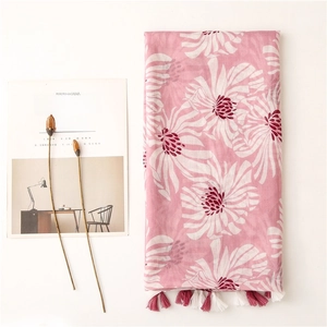 Détail d'une écharpe en lin rose à motifs floraux avec franges et imprimés doux