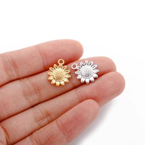 Macro detail of gold and silver sunflower charms held in hand to show the actual size