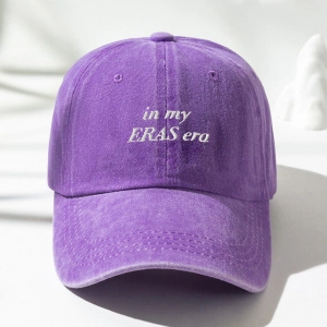 Close-up of purple washed cotton baseball cap with white In My Eras Era embroidery