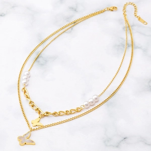 Elegant gold double-layered butterfly and pearl necklace on white marble background