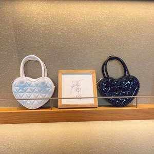 Close-up of heart-shaped quilted handbags in black and white on a wooden shelf