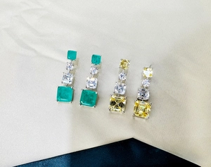 Detail view of 925 silver drop earrings featuring square emerald and yellow cut gemstones
