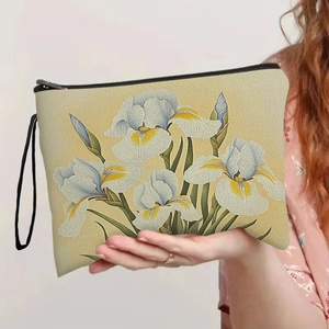Iris floral makeup bag with black zipper and wristlet strap held by a model