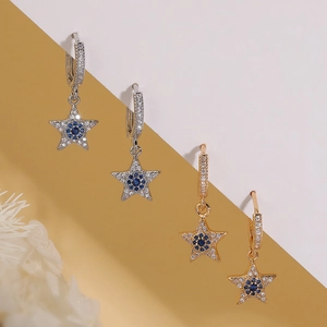 Star earrings with blue zircon and pavé stones in gold and silver finish on a neutral background