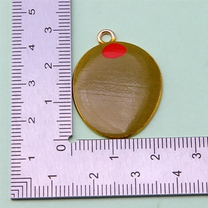 Detailed view of olive-shaped charm with green finish and red dots on a scale