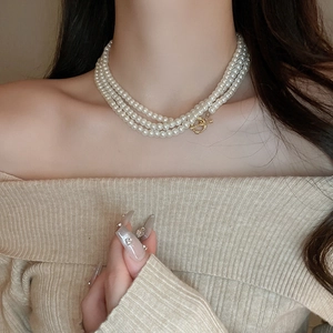 Detail of multi-layered pearl necklace featuring a classic gold OT toggle clasp on model