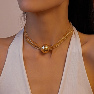Detail of multi-layered gold choker necklace with a large polished metallic spherical pendant