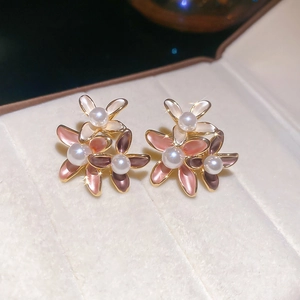 Macro shot of 18K gold plated flower earrings with pearl centers and enamel petals