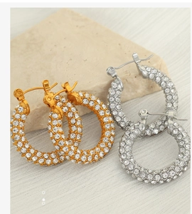 Gros plan de boucles d'oreilles créoles dorées et argentées serties de strass brillants