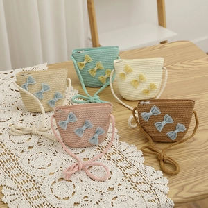 Detail of five mini straw bags in pastel colors with lace bows on a vintage lace cloth