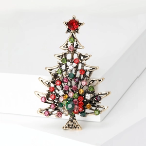 Vintage gold Christmas tree brooch with colorful rhinestones on a minimalist background