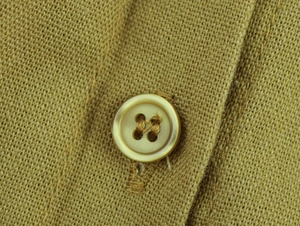 Macro shot of ginger yellow linen fabric showing texture and four-hole resin button detail