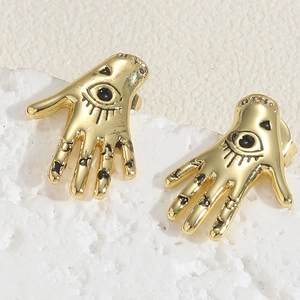 Macro shot of 14K gold Hamsa Hand stud earrings with black evil eye and stones on stone