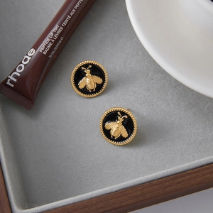 Vue détaillée des boucles d'oreilles abeille plaquées or 18K avec émail noir sur plateau