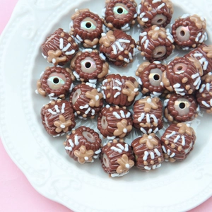 Detailed top view of chocolate-style cylinder loose beads on a vintage white plate