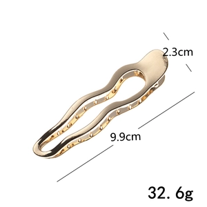 Detail showing wave-shaped gold metal hair claw clip with size dimensions 9.9cm and 2.3cm
