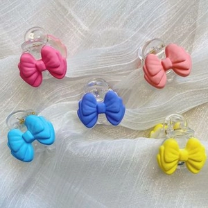 Detail of 5-piece colorful bow hair clips on white fabric showing various candy colors