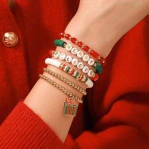 Ensemble de bracelets de Noël en argile rouge et verte portés sur un pull rouge