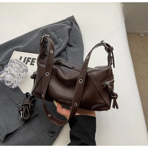 Detail of dark brown vintage faux leather shoulder bag with silver eyelets and twin zippers