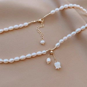 Detail of freshwater pearl necklace with floral pendant on beige silk background