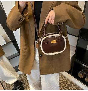 Detail of a brown leather pillow bag with white fleece trim worn as a crossbody purse