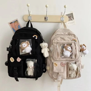 Detail of nylon backpacks in black and beige with clear pockets and plush decorations
