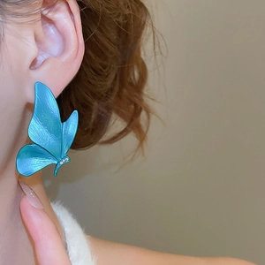 Detail of a large dark blue butterfly pendant earring worn by a model on side view