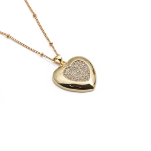 Close-up of heart pendant with sparkling clear zircons and delicate beaded gold chain