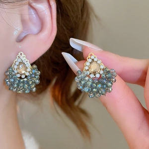 Détail de la boucle d'oreille en éventail avec strass champagne et perles bleu-gris