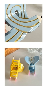 Macro detail of pencil hair claw clips featuring gold glitter stripes and blue acetate
