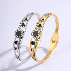 Detail view of gold and silver steel bangles with black enamel center and diamond accents