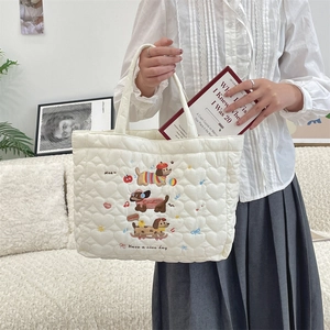 Detail of cute dog embroidery and quilted texture on a cream white fabric handbag