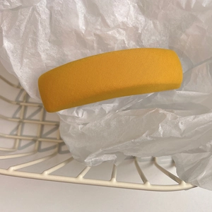 Macro shot of a yellow wide fabric headband placed in a white grid basket for hair styling