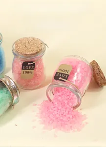 Close-up of pink Himalayan bath salt crystals pouring from a corked glass bottle