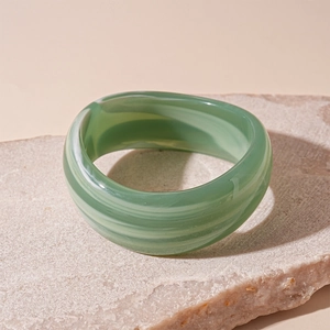 Macro shot of green and white marbled acrylic wide bangle on a natural stone base