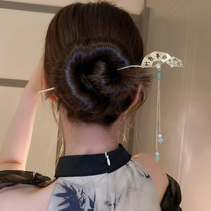 Detailed shot of silver hair pin featuring hollow fan charm and long jade tassel