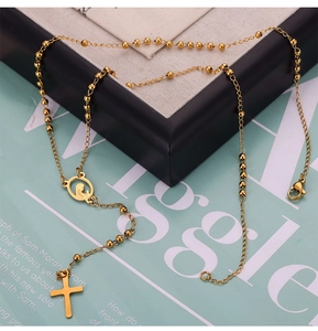 Detail of gold rosary necklace with cross pendant and virgin mary medal on textured surface