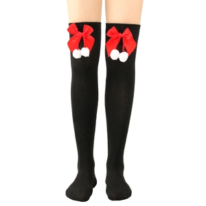 Detail of black over-knee socks featuring red satin bows and white fuzzy pom-poms accents