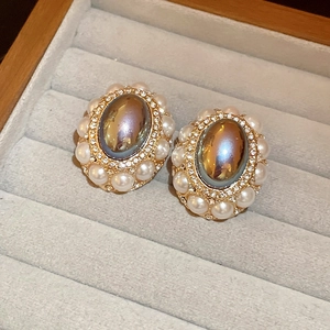 Vintage oval pearl stud earrings with colorful stone and gold plating on grey tray