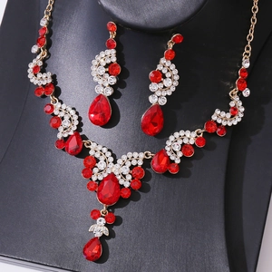 Close-up of gold-tone bridal jewelry set with red teardrop crystals and white rhinestones