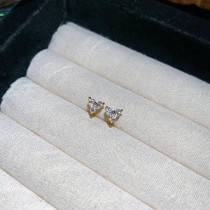 Macro view of gold flower earrings with three zircon stones in a velvet jewelry box