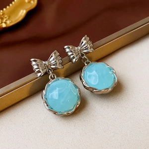 Dettaglio macro di orecchini vintage in resina blu con fiocco argento e bordi