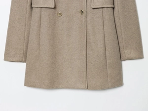 Detail of oatmeal wool blend coat featuring double-breasted gold metal buttons